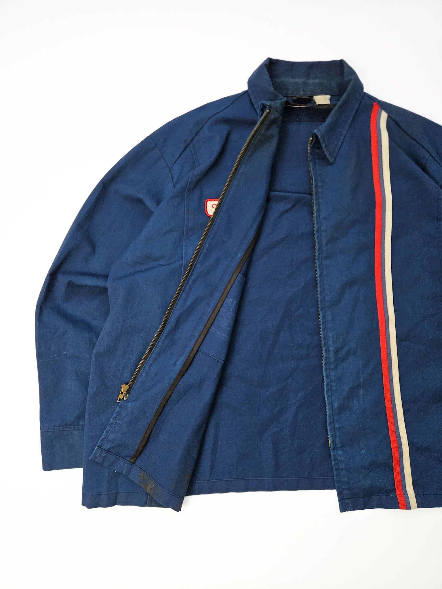 1970s Atlas Van Lines vintage work jacket in donkerblauw met rood-wit-blauwe racestreep en Marty naamlabel, vooraanzicht flatlay