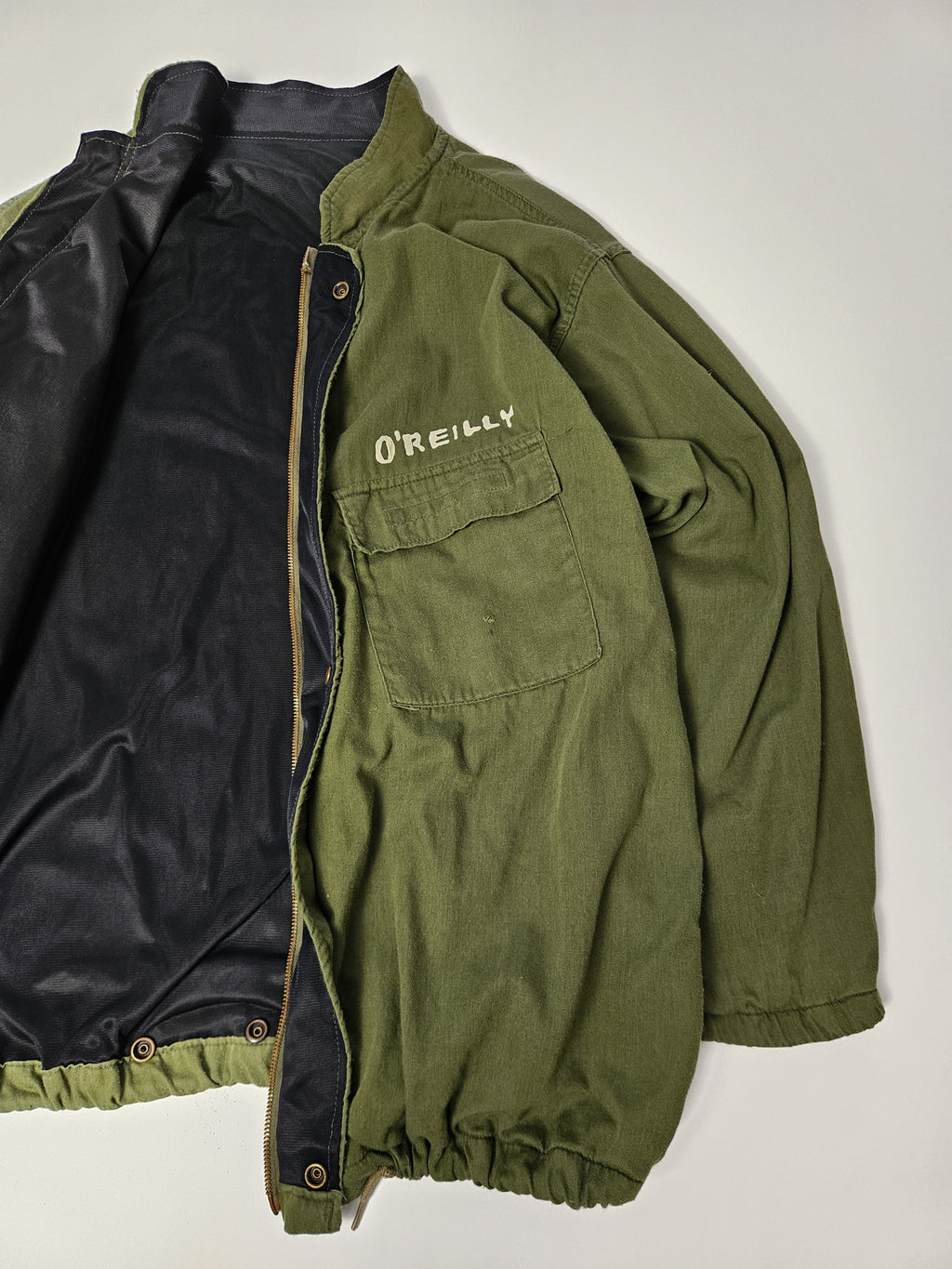 Flatlay van de vintage MASH field jacket met army styling, borstpatch en klassieke schouderepauletten*

