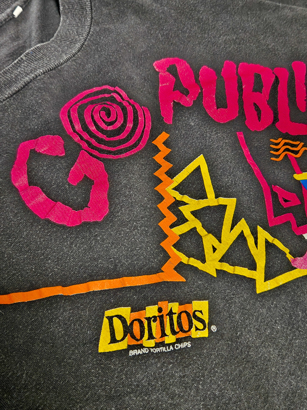 Close-up van de Doritos Go Public print op vintage T-shirt, met textuur en logo