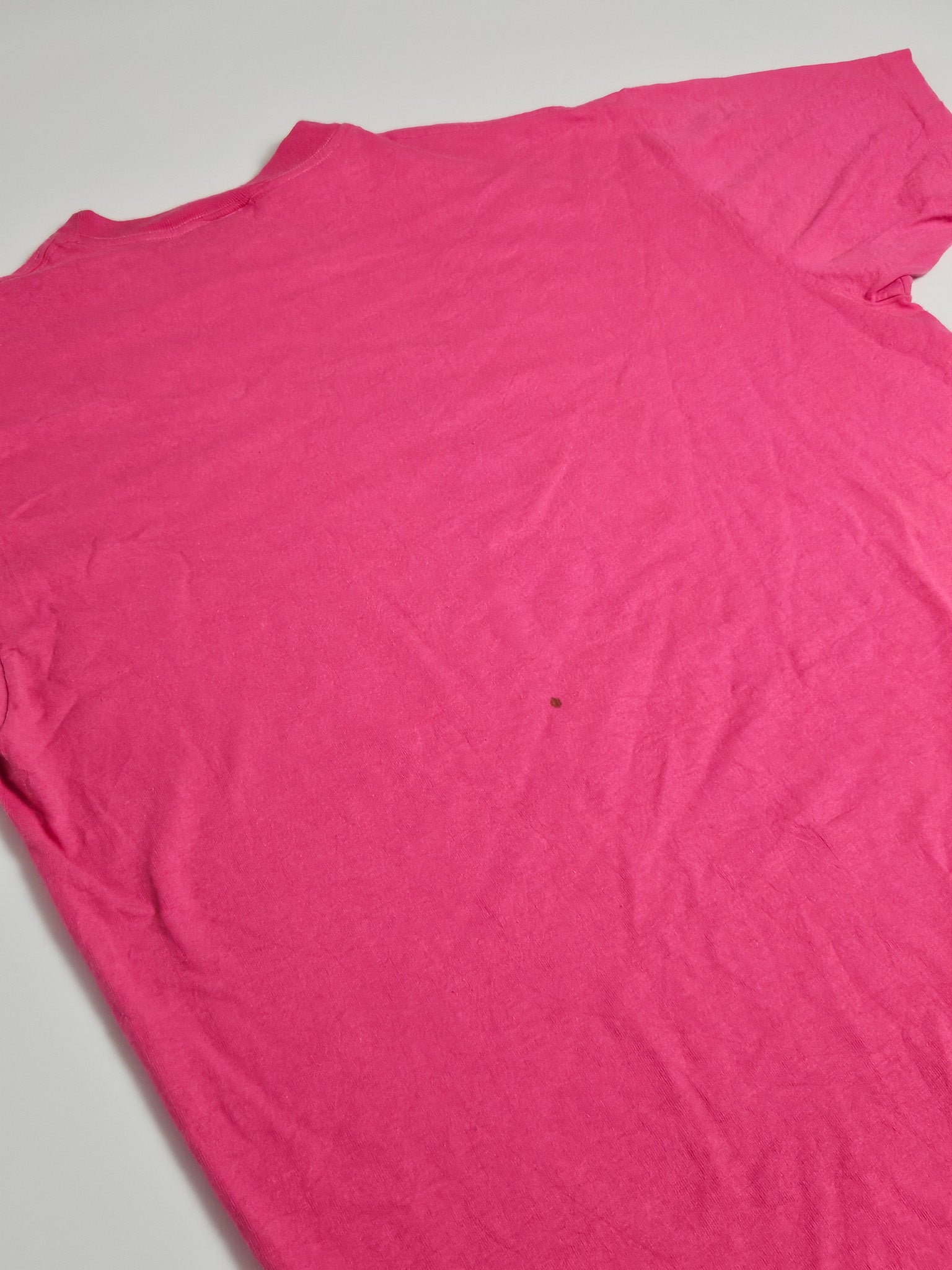 Detail van de felroze stof van vintage Tony Robbins T-shirt met klein vlekje op de rug