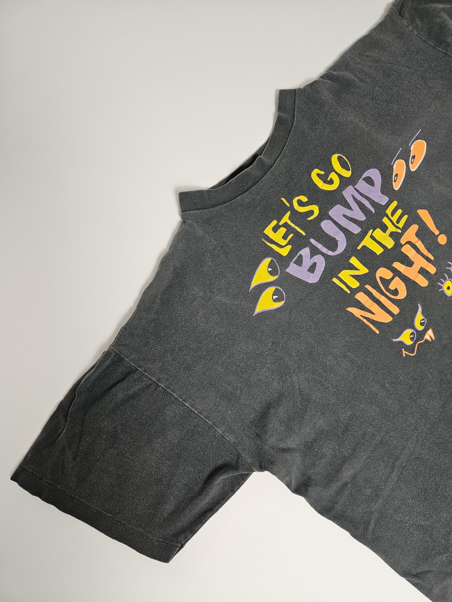 Zijaanzicht van vintage T-shirt met "Let's Go Bump in the Night" print op de schouder