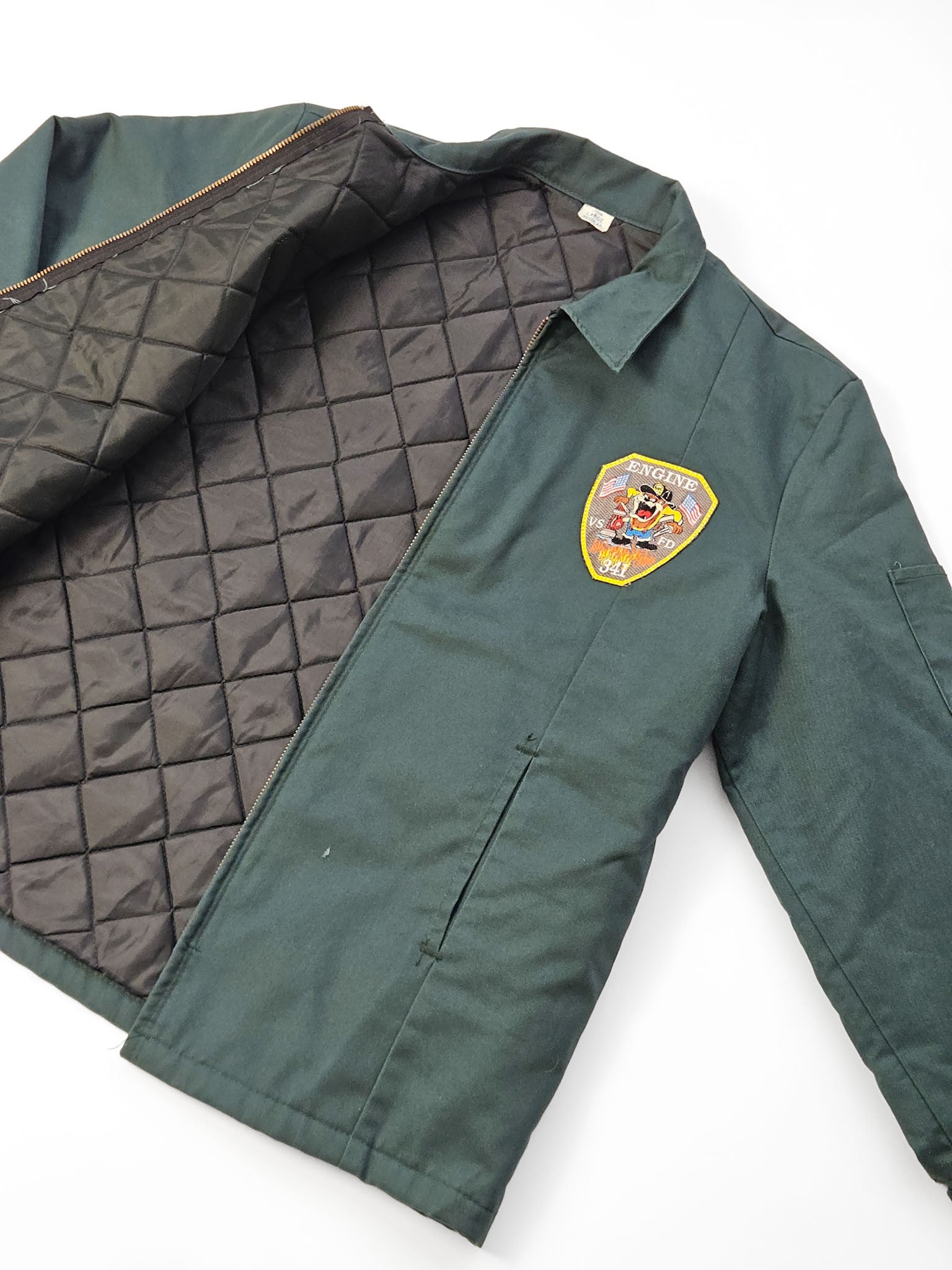 1990s VSFD Engine 341 vintage brandweer-werkjas in donkergroen met Taz-patch en Justin naamlabel, vooraanzicht flatlay