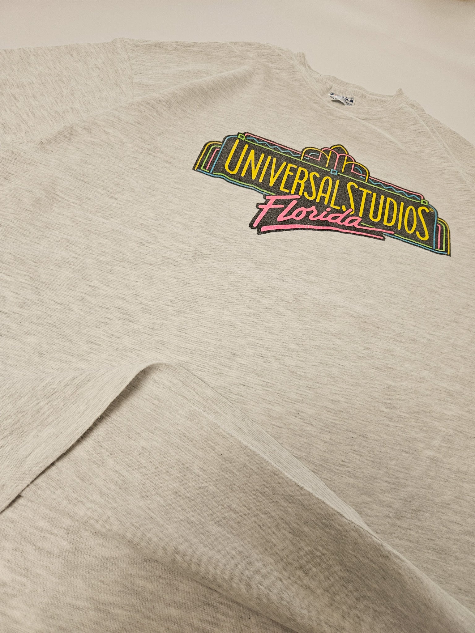 Flatlay van het grijze vintage Universal Studios T-shirt uit de jaren 90 met gekleurde frontprint
