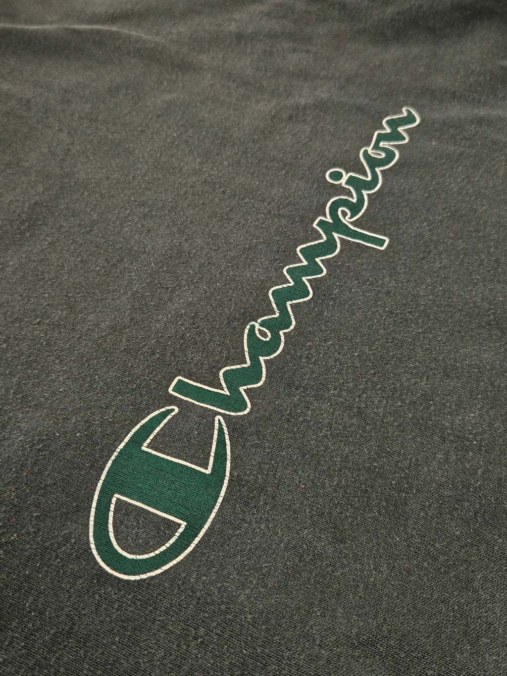 Close-up van het Champion script logo op de borst met craquelé print
