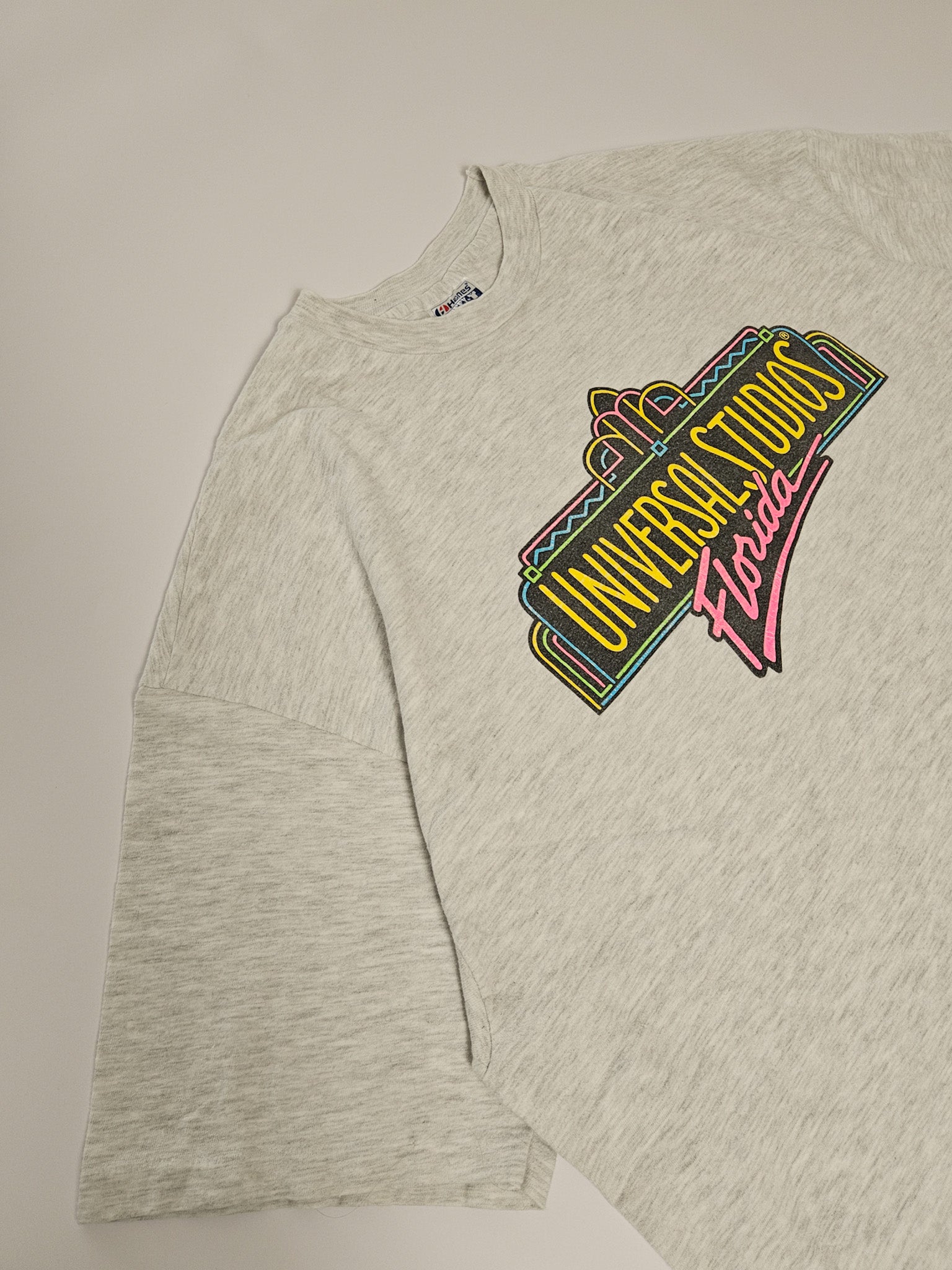 Flatlay van het grijze vintage Universal Studios T-shirt uit de jaren 90 met gekleurde frontprint
