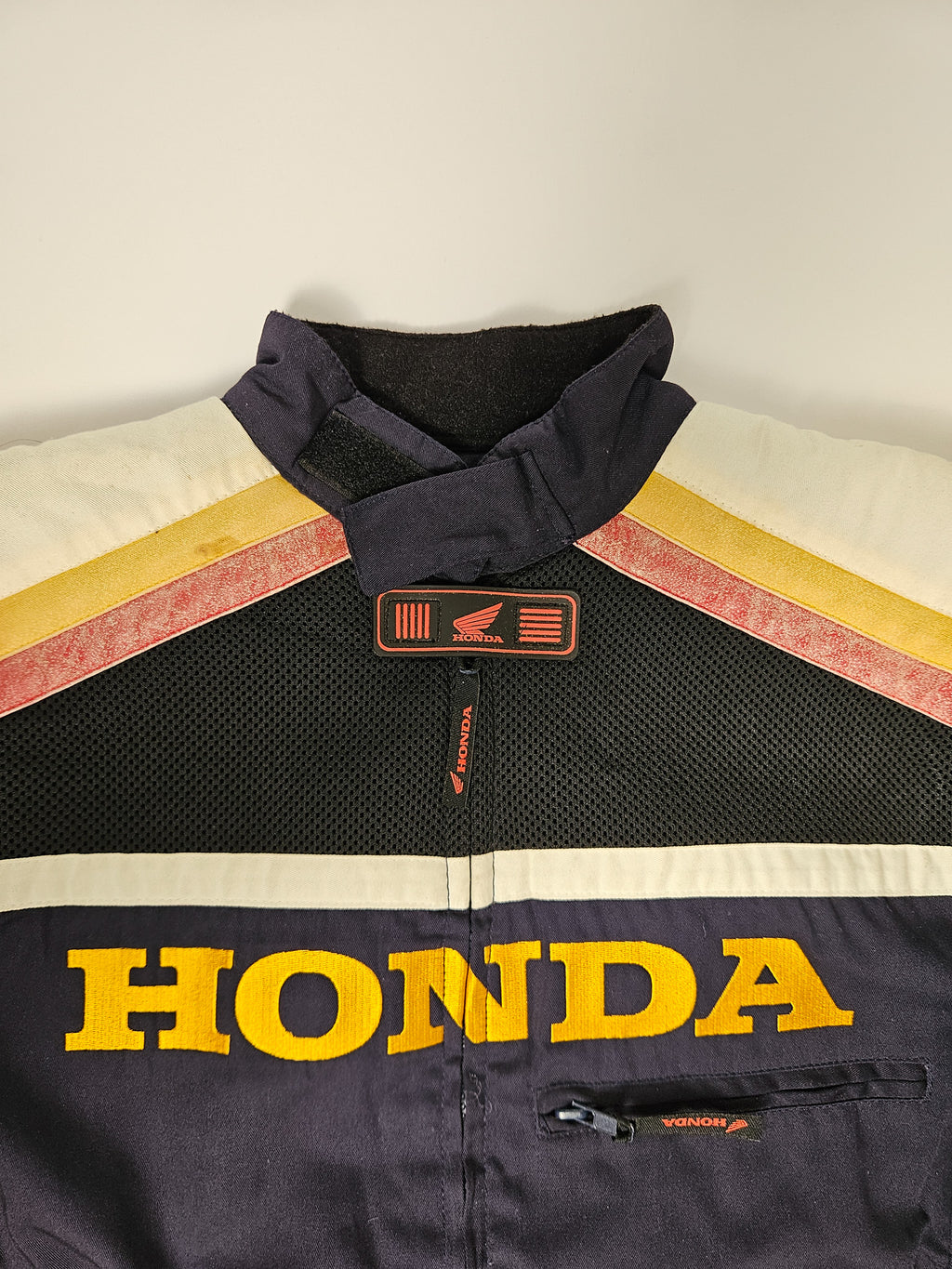 Detail van het Honda Racing logo en teampatches op de borst van de jas, met zichtbare slijtage van gebruik

