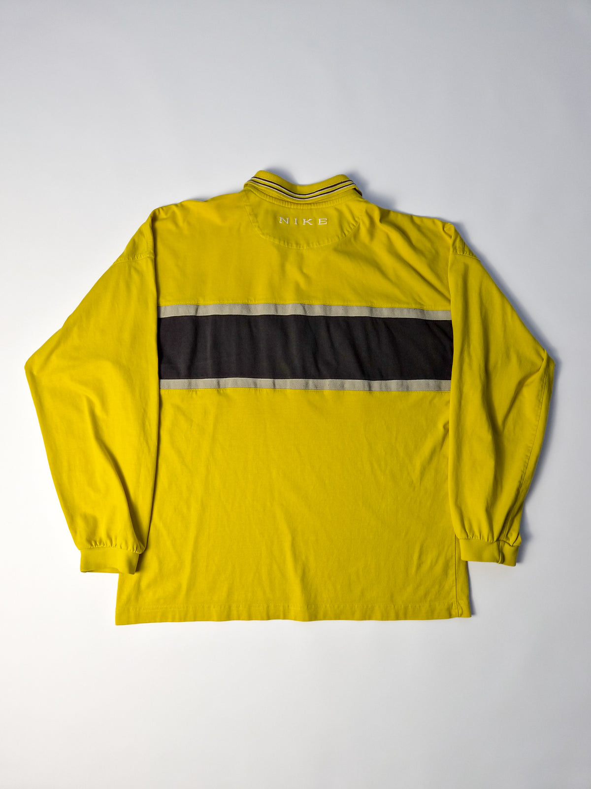Geel vintage Nike rugby shirt uit de jaren 90 met zwart-wit colorblock rugpaneel en geborduurd NIKE-logo in de nek.