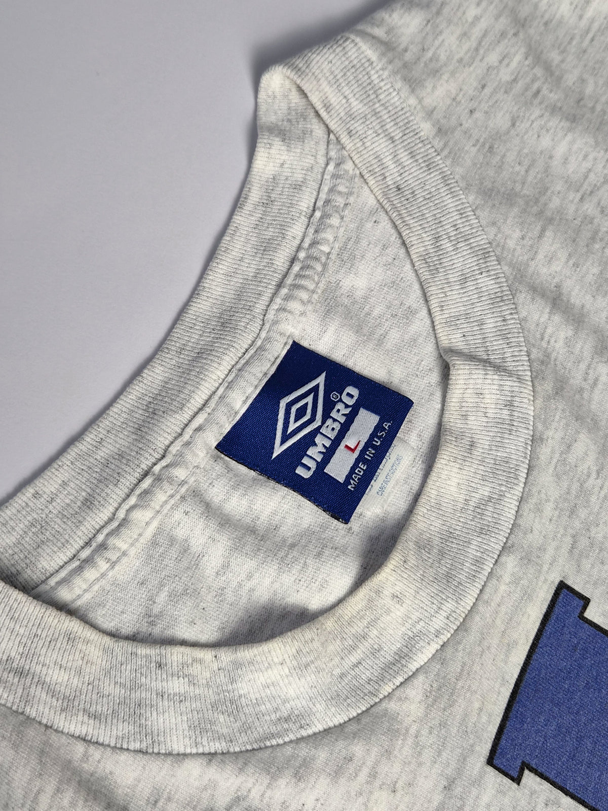 Blauw geweven Umbro-label met het double diamond-logo, maat L en de vermelding Made in U.S.A.