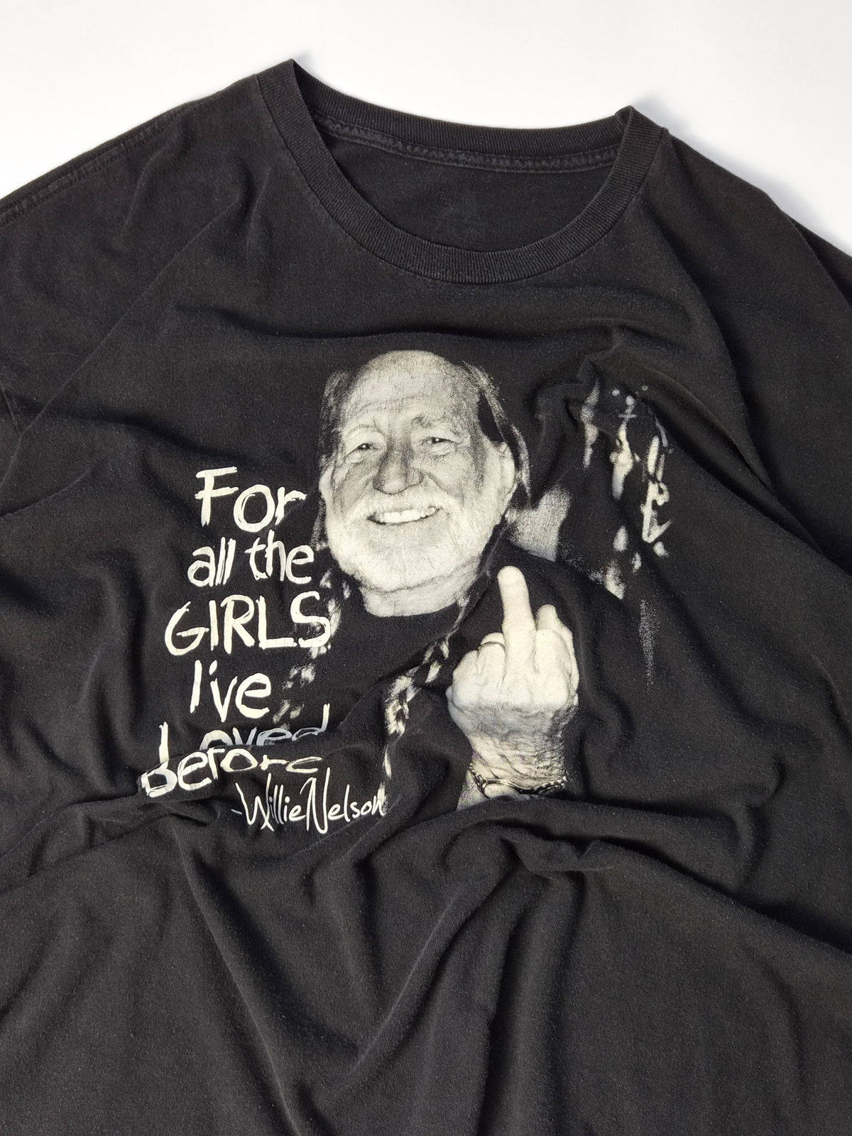 Vintage Willie Nelson graphic tee uit circa 2000 in zwart met close-up van de monochrome middle finger zeefdruk en lichte craquelure.